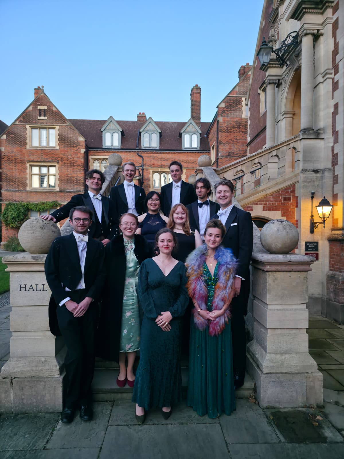 The club gathered in white tie and evening dress on the steps outside Hall at dusk