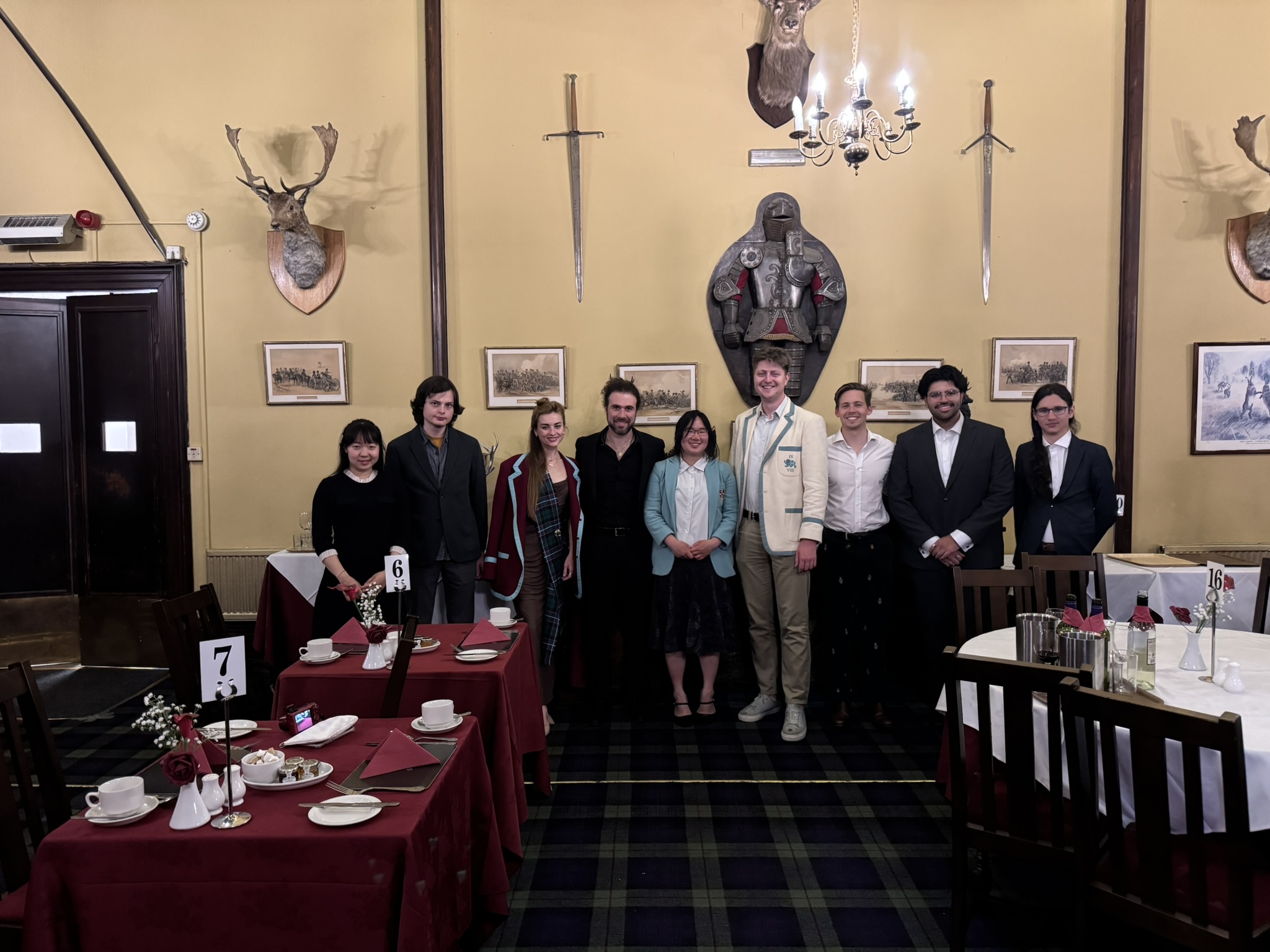 Members in black tie in a tartan-carpeted dining room hung with stag heads and swords