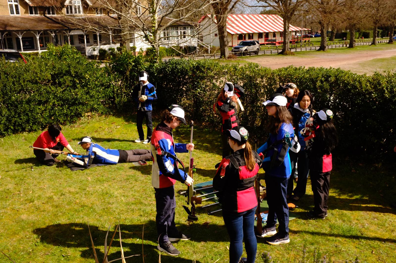 Members in shooting jackets waiting with their rifles on the lawn outside the clubhouse