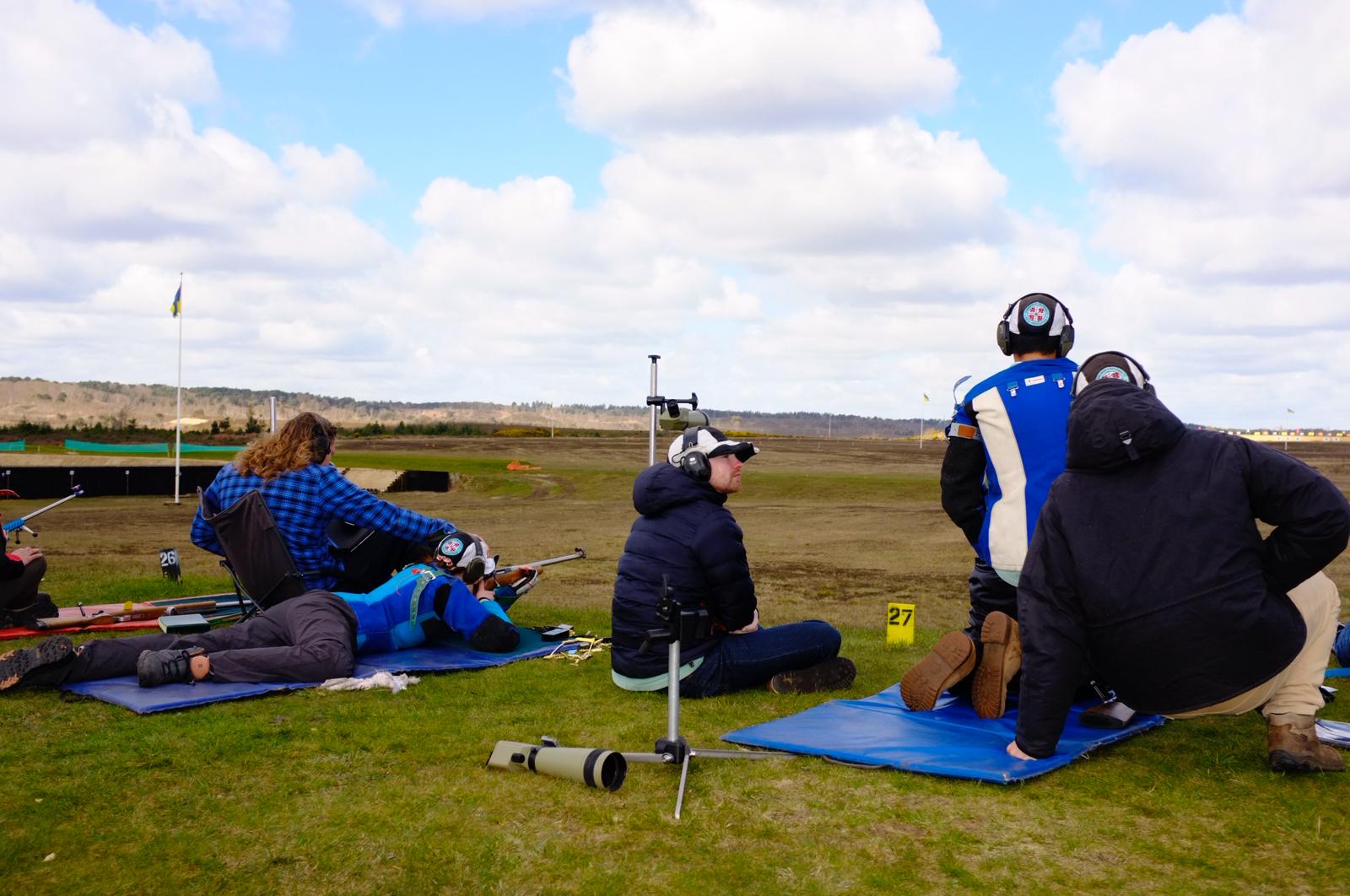 Members shooting and coaching from mats on the firing point at Bisley, spotting scopes set up alongside